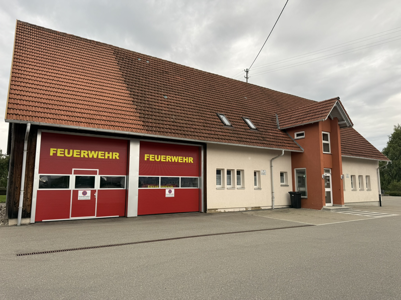 Feuerwehrhaus Beffendorf. Frontansicht mit zwei modernen großen Garagentoren. Gelber Aufdruck auf den Toren mit "Feuerwehr"