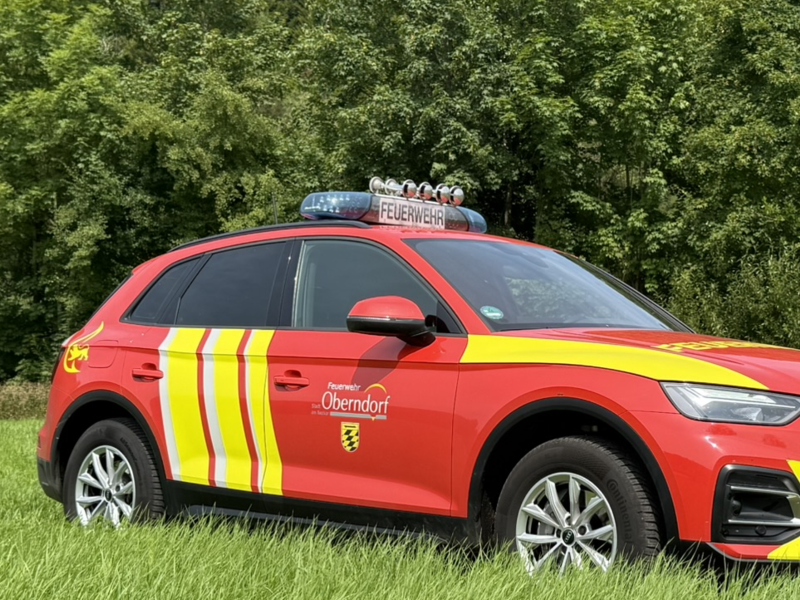Audi Viertürer in rot-gelben Feuerwehrfarben. Sirenen sind auf dem Dach. Seitenansicht. 