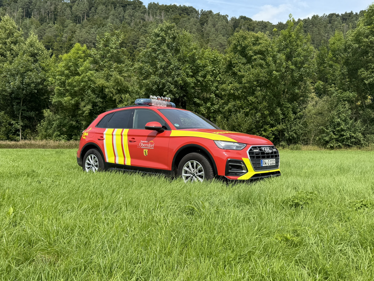 Audi Viertürer in rot-gelben Feuerwehrfarben. Sirenen sind auf dem Dach. Seitenansicht. 