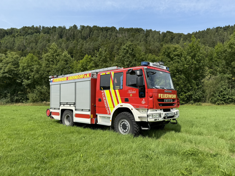 Feuerwehr-Löschfahrzeug steht auf einer Wiese. Seitenansicht mit drei Rolltoren. Schriftzug Feuerwehr Oberndorf a.N. Auf der Frontscheibe steht die Fahrzeugnummer 1/46 