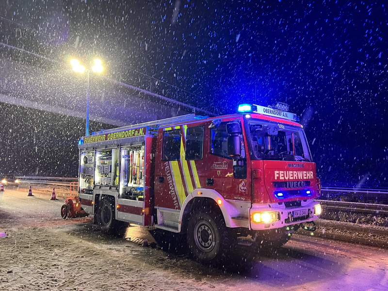 Hilfeleistungslöschfahrzeug bei Schneetreiben mit eingeschaltetem Blaulicht und ausgefahrenem Lichtmast.