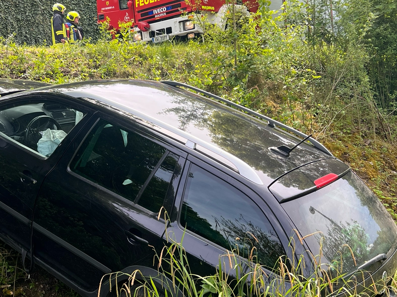 Rüstwagen steht oberhalb einer Einsatzstelle. Ein abgestürztes Auto ist zu sehen.