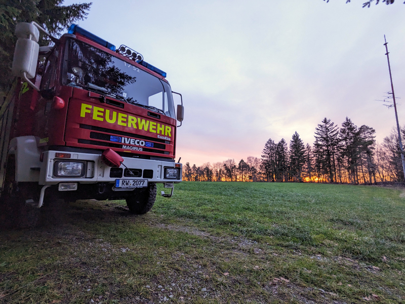 Rüstwagen steht bei Sonnenuntergang auf einer Wiese. 