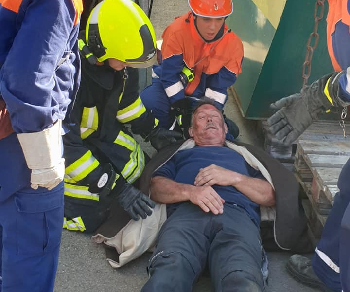 Verletzter älterer Mann liegt am Boden. Jugendliche in Feuerwehrkleidung üben Rettungsaktion.
